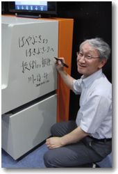 「はやぶさシミュレータ」にサインをするJAXA川口淳一郎氏。